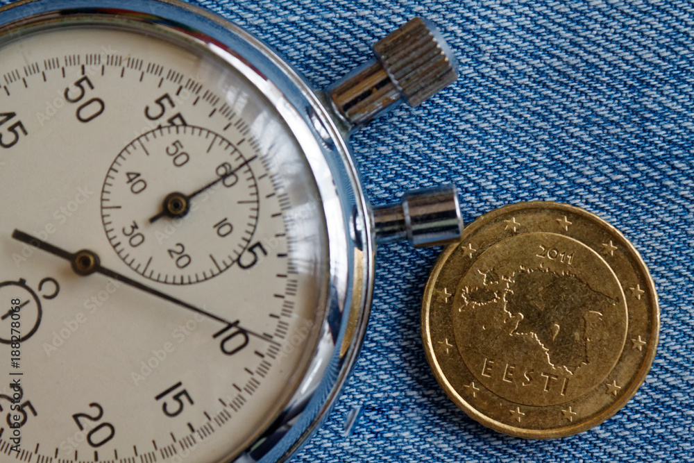 Euro coin with a denomination of fifty euro cents (back side) and stopwatch on blue denim backdrop - business background