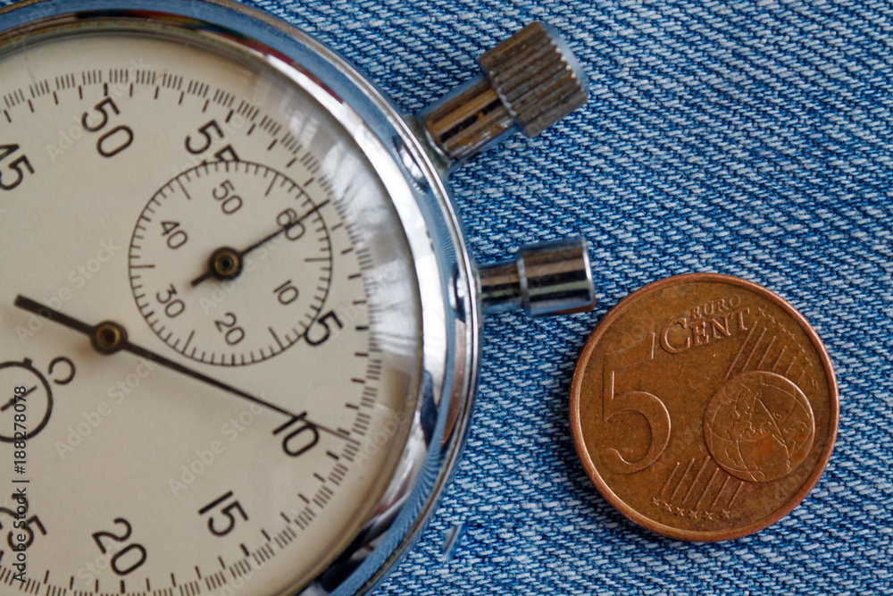 Euro coin with a denomination of 5 euro cents and stopwatch on blue denim backdrop - business background Euro coin with a denomination of 5 euro cents and stopwatch on blue denim backdrop - business background