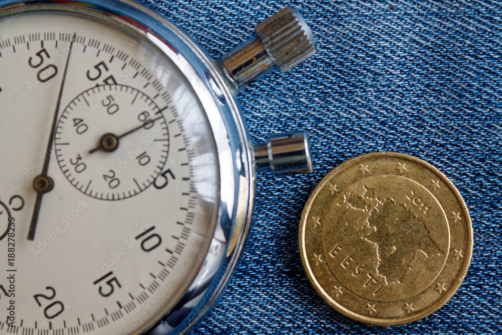 Euro coin with a denomination of fifty euro cents (back side) and stopwatch on worn blue denim backdrop - business background