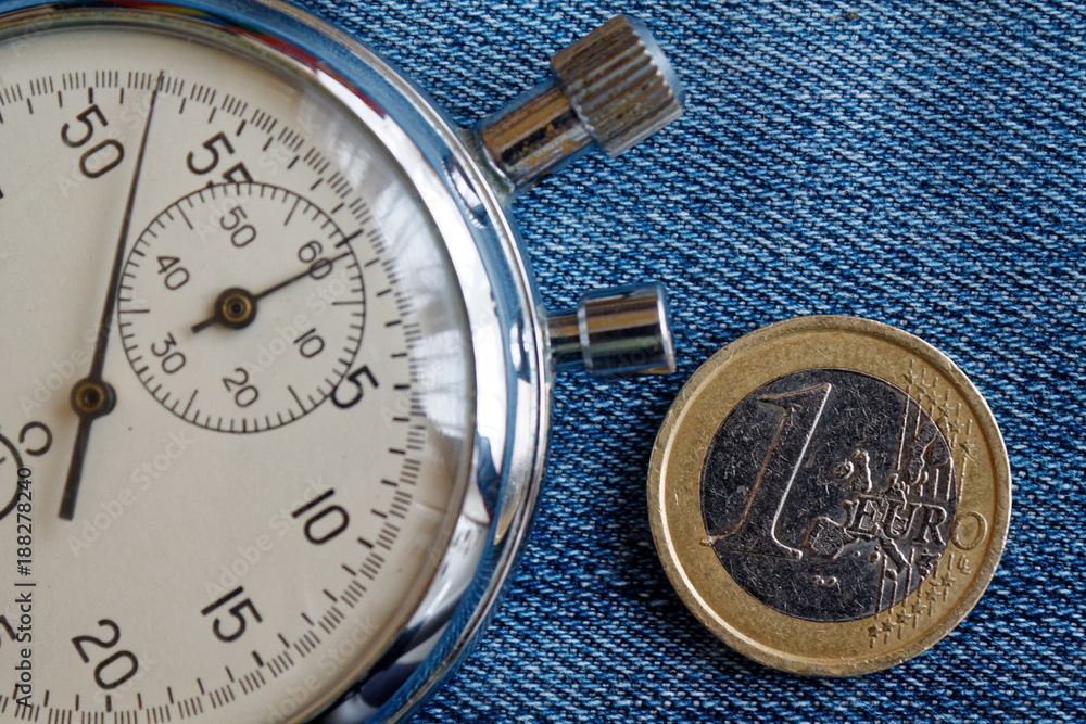 Euro coin with a denomination of 1 euro and stopwatch on worn blue denim backdrop - business background
