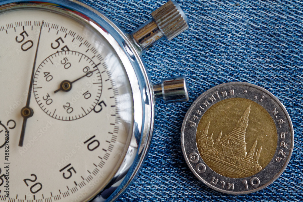 Thai coin with a denomination of 10 baht and stopwatch on old blue denim backdrop - business background