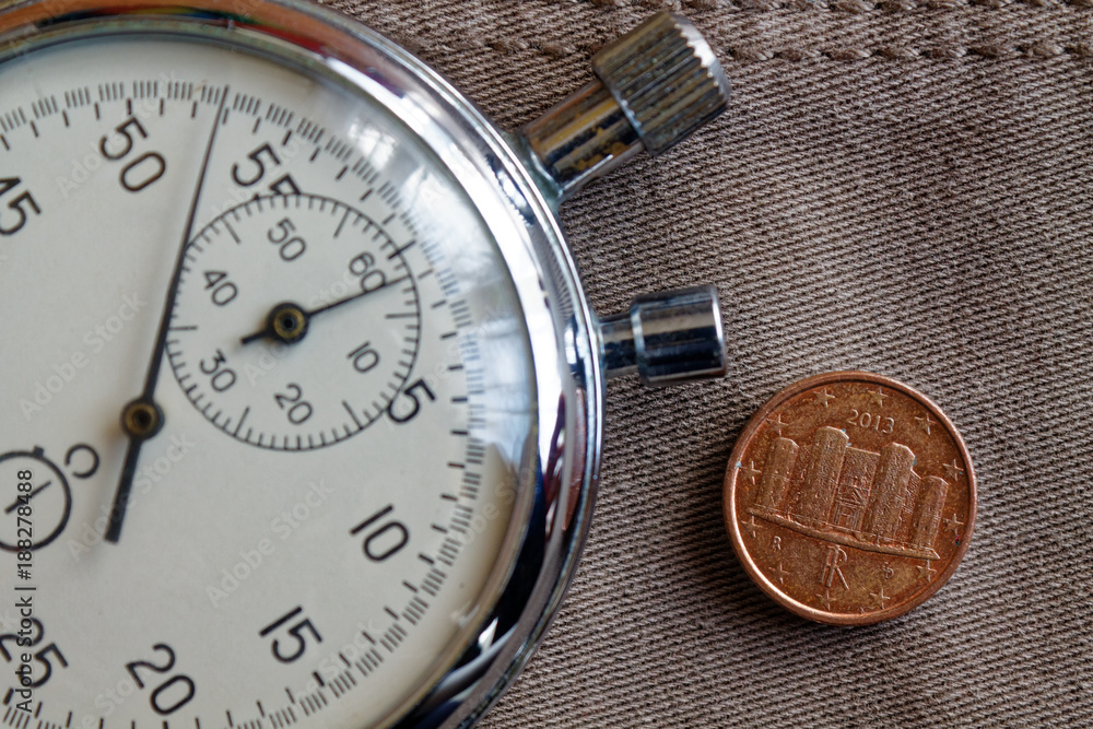 Euro coin with a denomination of one euro cent (back side) and stopwatch on old beige jeans backdrop - business background