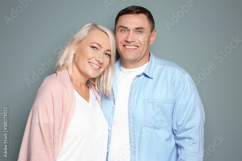 Cute middle-aged couple on color background