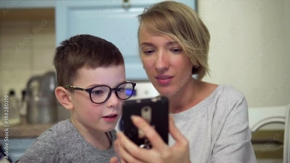 Close-up of mother and son amazedly looking at smartphone screen Close-up of mother and son amazedly looking at smartphone screen