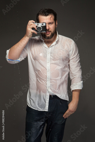 Portrait of a wet photographer with a camera in the studio