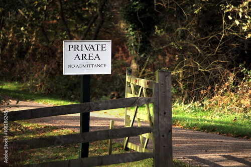 Wooden gate on a road through forest or woodland, with a sign saying "PRIVATE AREA No Admittance"