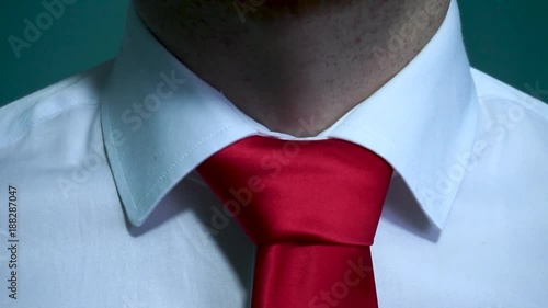 Caucasian man with white shirt fixing his red tie