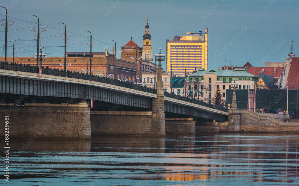 Naklejka premium Picturesque view on the modern architecture of Riga panorama over the river with blue sky in background. Lights creating reflections in river.