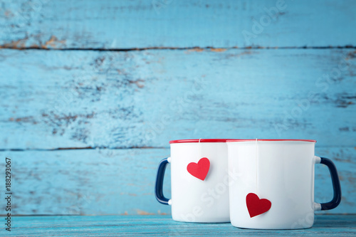 Mugs of tea with red heart on wooden table
