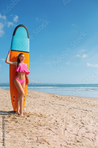 Surfer, girl in a pink swimsuit with a board on the beach. The concept of vacation. Summer vacation. Tourism, sports.