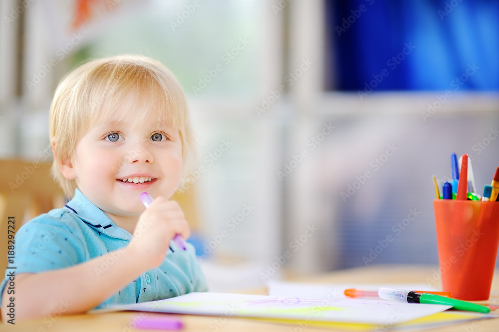 Cute little boy drawing and painting with colorful markers pens at kindergarten Cute little boy drawing and painting with colorful markers pens at kindergarten