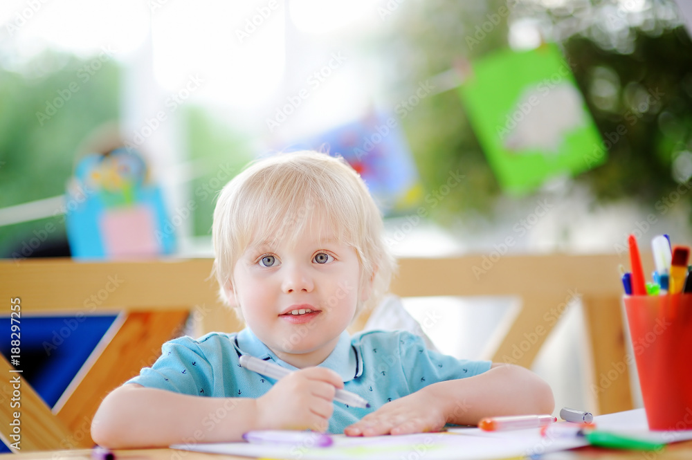 Cute little boy drawing and painting with colorful markers pens at kindergarten Cute little boy drawing and painting with colorful markers pens at kindergarten