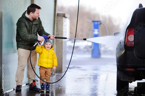 Middle age man and his little son washing a car on a carwash
