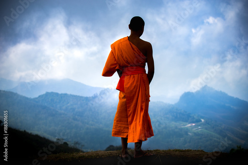 Fototapet The young Thai monk standing over landscape in Thailand.