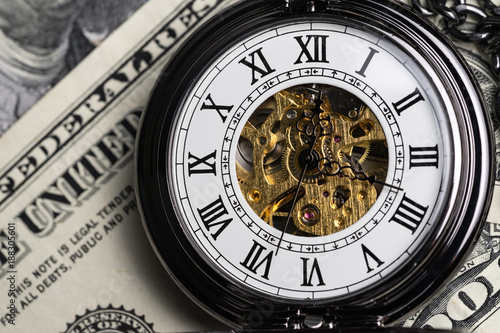 Closed up of mechanical vintage pocket watch on US dollar banknotes background as time for invest concept