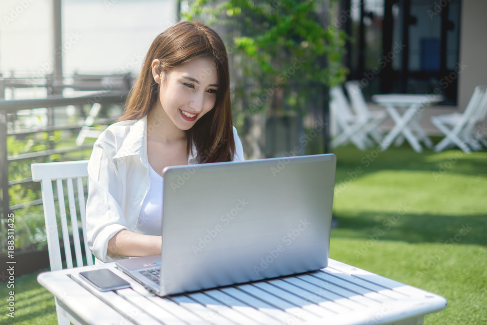 Beautiful Asian self employed or freelance business woman working with her laptop PC at the restaurant terrace Beautiful Asian self employed or freelance business woman working with her laptop PC at the restaurant terrace