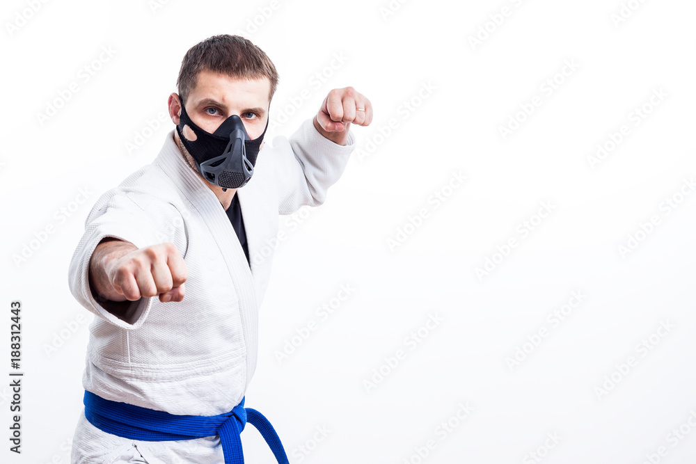 Naklejka premium Young man fighter in a white kimono with blue belt for judo, jujitsu pose on isolated white background