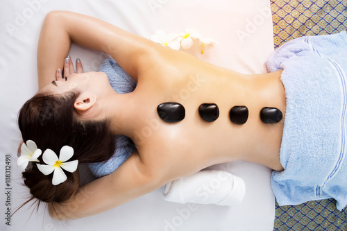 Hot stone on back of asian pretty woman in spa room photo