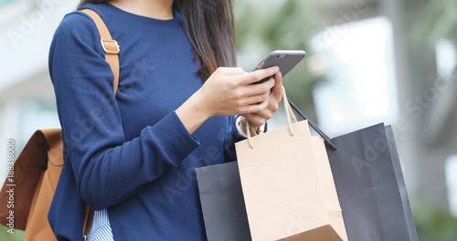 Woman holding paper bag with mobile phone
