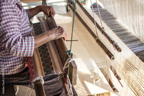 Woman weaving silk in traditional way at manual loom. Thailand