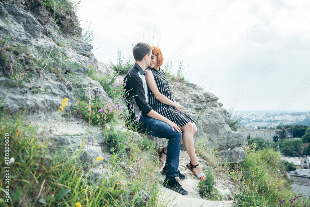 young woman sits with her boyfriend on the peak of the hill