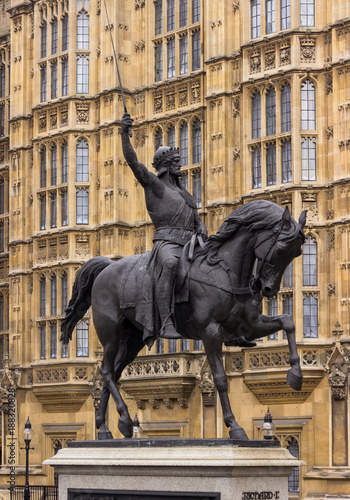 Sword raised in the air astride a prancing horse, Richard the Lion Heart is depicted outside of the British Parliament building.