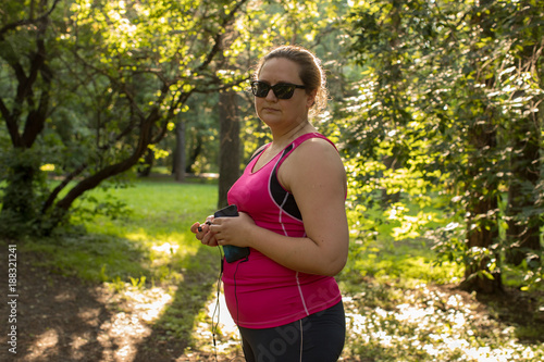 Overweight woman lookingat the camera in the park with listening to music. Weight loss concept. photo