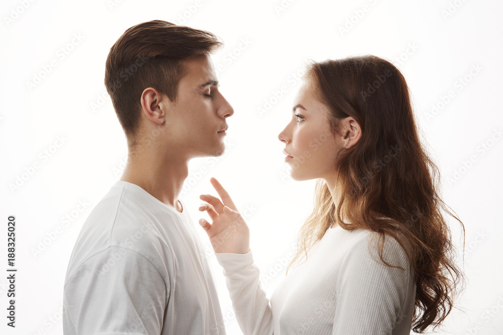 Concept of love tenderness and romance. Young romantic couple standing in front of each other. Girl wants to reach him and boyfriend is nervously awaiting for her kind touch. Concept of love tenderness and romance. Young romantic couple standing in front of each other. Girl wants to reach him and boyfriend is nervously awaiting for her kind touch.