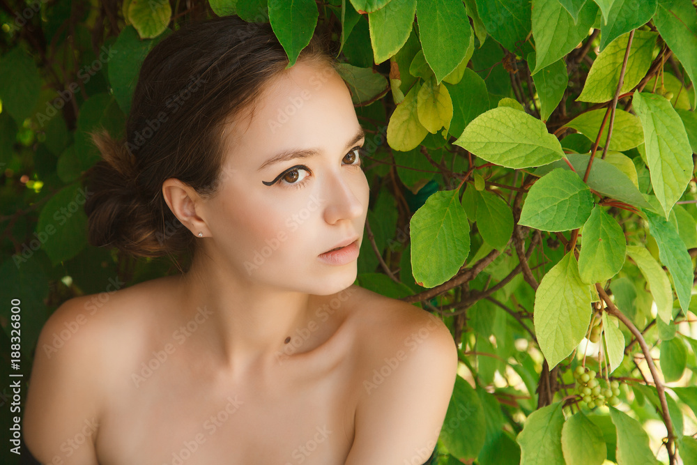 Portrait of a girl with bare shoulders covering her eyes with a leaf Portrait of a girl with bare shoulders covering her eyes with a leaf