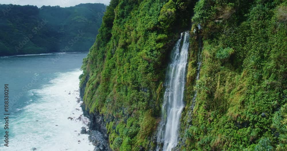 Cinematic aerial view of dramatic waterfall on sea cliff into the ocean Cinematic aerial view of dramatic waterfall on sea cliff into the ocean