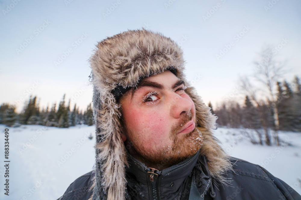 Close-up portrait of middle aged man adventurer with frosted beard in forest or tundra during winter expedition Close-up portrait of middle aged man adventurer with frosted beard in forest or tundra during winter expedition