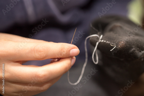 A girl sews a sock with a needle