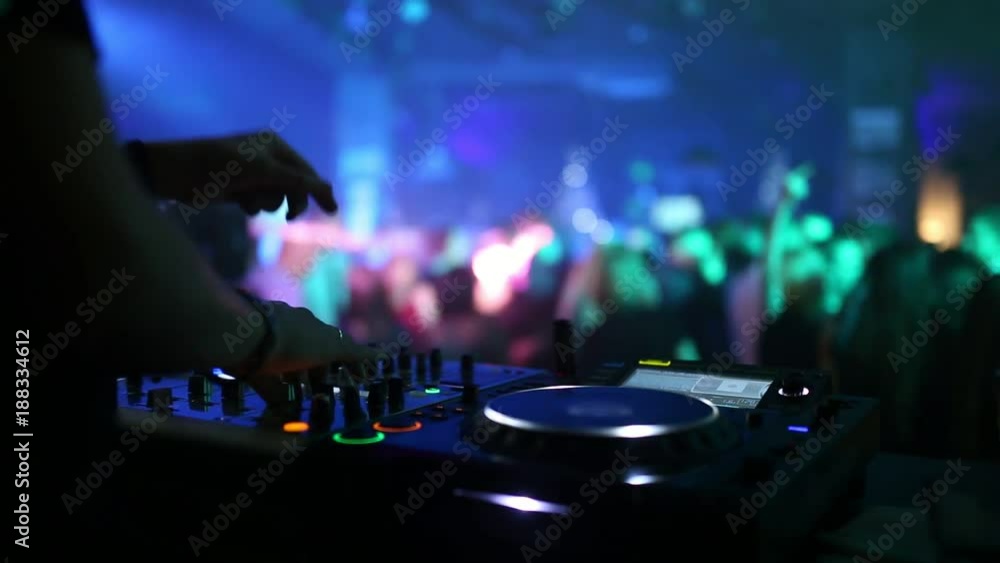 In the foreground is a sound mixer for the work of a DJ, and on the background of the back, dancing people. In the foreground is a sound mixer for the work of a DJ, and on the background of the back, dancing people.