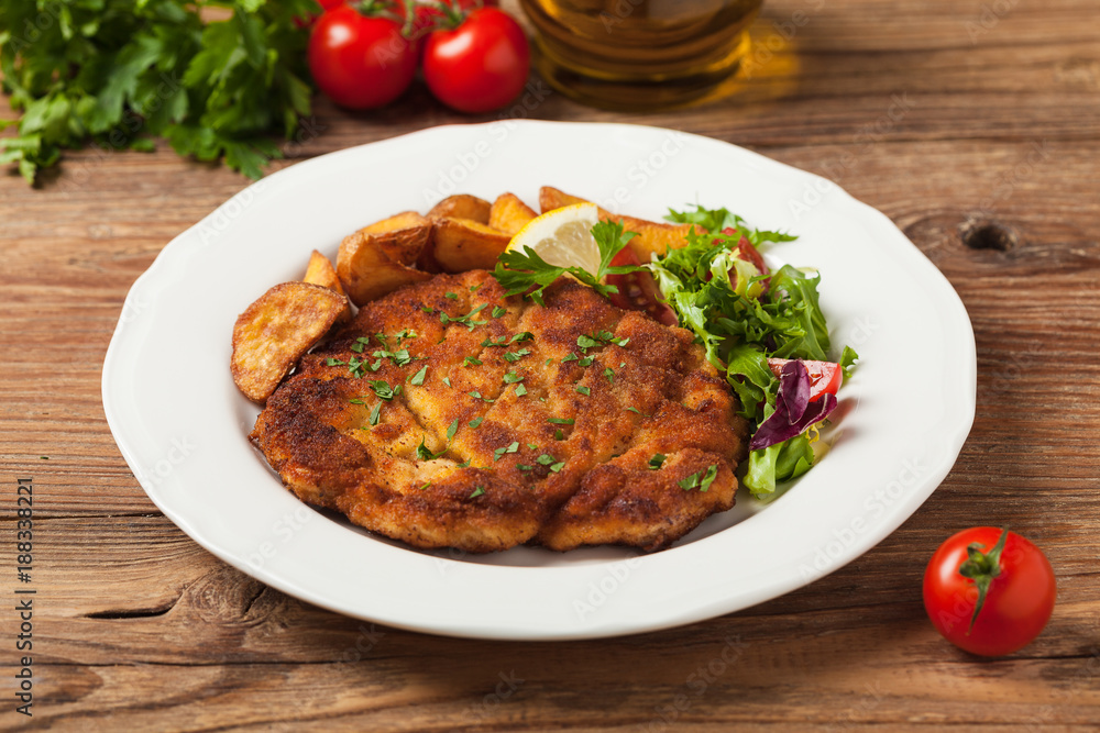 Chicken schnitzel, served with roasted potatoes and salad. Chicken schnitzel, served with roasted potatoes and salad.