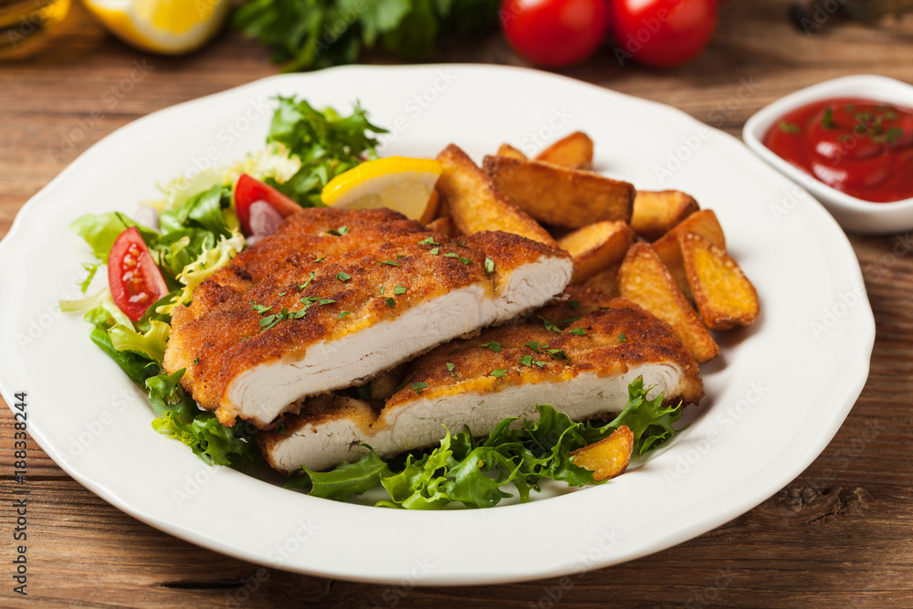 Chicken schnitzel, served with roasted potatoes and salad.