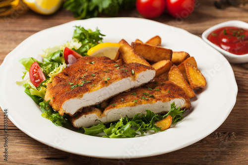 Chicken schnitzel, served with roasted potatoes and salad.