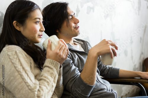 テレビを見ながらコーヒーを飲む若い夫婦