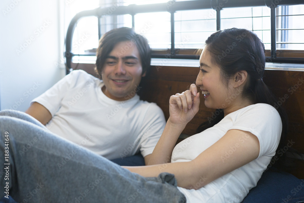 ベッドで談笑する若いカップル ベッドで談笑する若いカップル