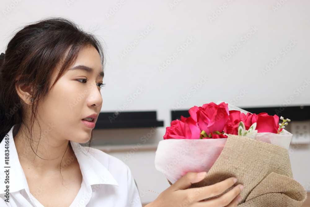 Cropped image of attractive young Asian woman accepting a bouquet of red roses from boyfriend in office on valentine's day. Love and romance in workplace concept. Cropped image of attractive young Asian woman accepting a bouquet of red roses from boyfriend in office on valentine's day. Love and romance in workplace concept.