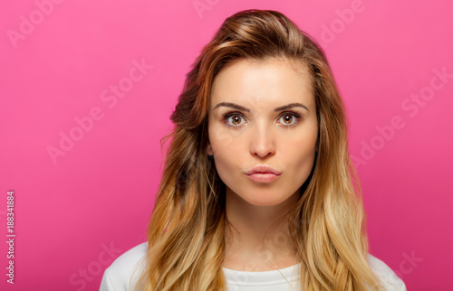 Funny portrait of beautiful girl with long hair on pink background