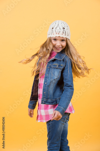 Girl in jeans suit, hat, plaid shirt on orange background
