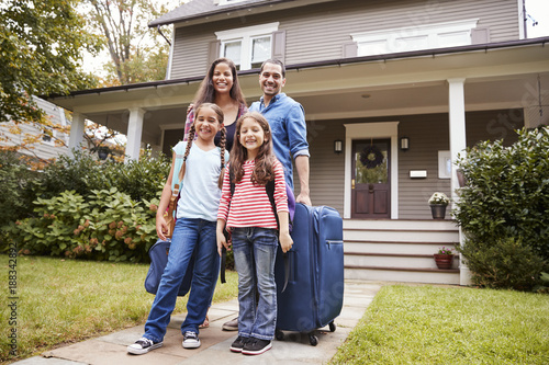 Portrait Of Family With Luggage Leaving House For Vacation