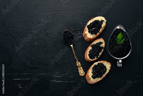 Sandwich with black caviar and butter. On a wooden background. Top view. Free space for text.