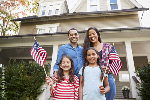 Portrait Of Family Outside House Holding American Flags photo