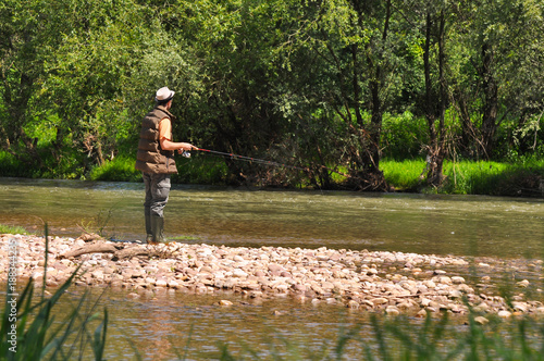 Man casts a hook on the river. Man fishing on wild river