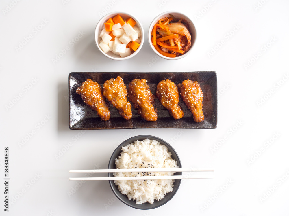 Φωτογραφία Deep fried chicken wing plate with garlic sauce in Korean style serve with rice, kimchi and pickled radish on white background in top view for asian food concept