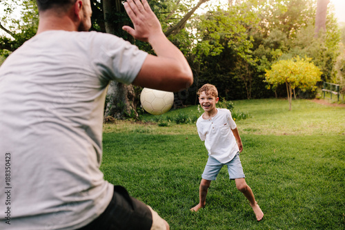 Happy young family playing with ball in backyard