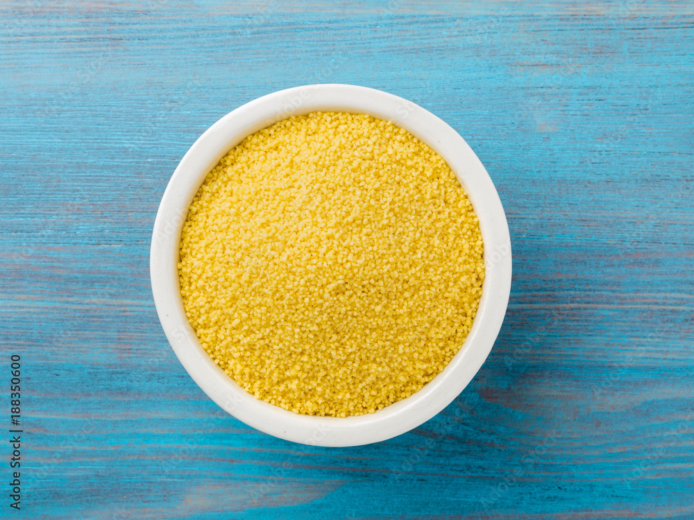 White bowl with raw couscous on blue wooden background, top view. Traditional Moroccan food White bowl with raw couscous on blue wooden background, top view. Traditional Moroccan food