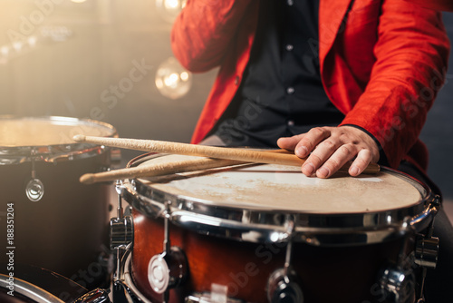 Male drummer in red suit sitting behind drum set