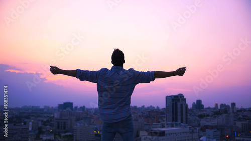 Man stretching hands on roof edge, enjoying freedom, believe in future success photo